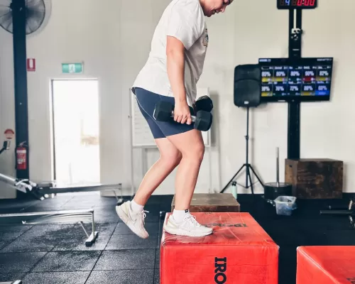 a woman lifting weights while standing on a box