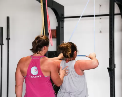 a woman doing her chest pulls with the help of a trainer