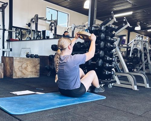girl sitting on the mat with weights
