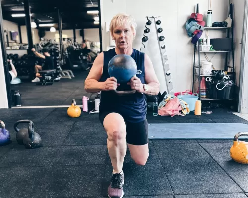 a woman doing her lunges while lifting her kettleball